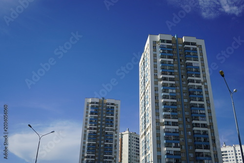 Tableau sur toile A panoramic view of modern residential high-rise buildings under a bright blue sky with a few clouds, showcasing urban architecture and design