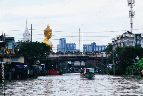 Bangkok Canal View with Tourist Boat and Giant Golden Buddha Statue at Wat Paknam from Phasi Charoen River Thailand