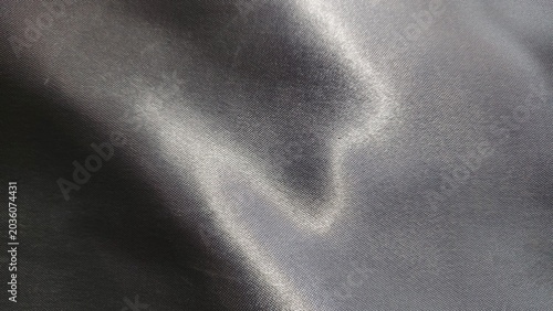Smooth silver satin fabric flows elegantly with soft reflections, creating a luxurious and modern abstract texture.