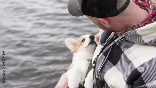 Young man enjoying walk with pembroke welsh corgi puppy by the river. Royal breed in trend, lifestyle and nature moment. Pets concept.