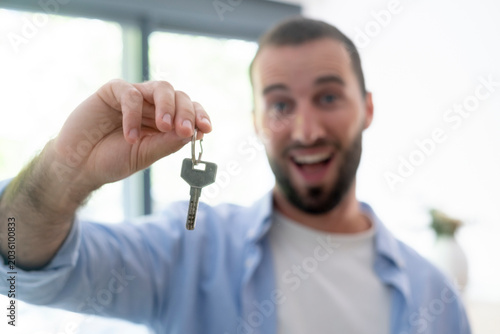 Fotografie Happy man holding keys celebrating new home ownership and moving into a house wi