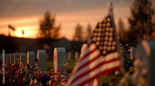 US flag and flowers at military cemetery headstones during sunset