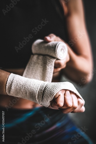 Obraz na plátně Female boxer putting a strap on her hand