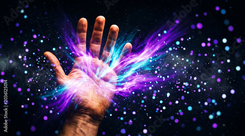 Human hand reaching out into a cosmic space filled with glowing nebula energy, stardust, and vibrant purple and blue light