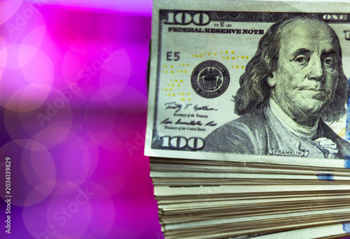 Εκτύπωση καμβά Thick stack of hundreddollar bills piled against neon pink backdrop, heavy bundle suggests bankroll or cash reserve, gritty texture contrasts with glamorous lighting of entertainment venue