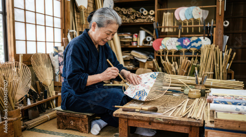 Senior Artisan Meticulously Painting a Traditional Japanese Fan.