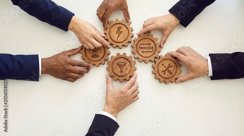 Team collaboration, business process, project management concept with hands arranging wooden gear icons.