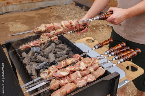Foto Man grilling shish kebab shashlik on the barbecue skewers