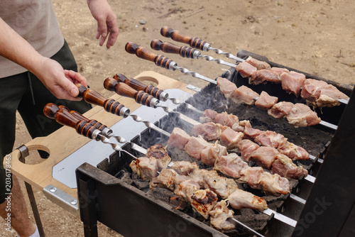 Tableau sur toile Man grilling shish kebab shashlik on the barbecue skewers