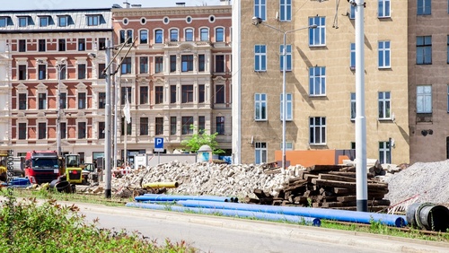 Bild auf Leinwand Urban road reconstruction site with blue pipes and old buildings in the backgrou
