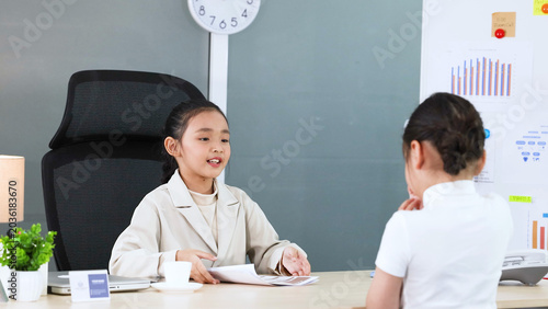 Fotografie Young Asian Girl in White Blazer Roleplaying as Business Executive in Office