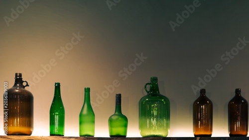 Картината върху платно Row of vintage glass bottles with warm bottom lighting background