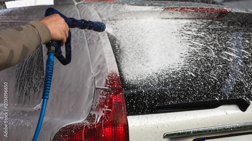 Car washing with a high pressure water jet at an outdoor self-service  car wash station.