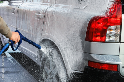 Car washing with a high pressure water jet at an outdoor self-service  car wash station.