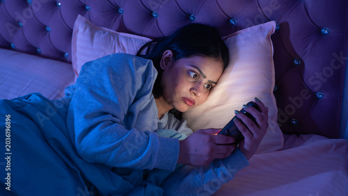 Indian Woman Using Phone Late at Night Lying in Bed in Dark Bedroom