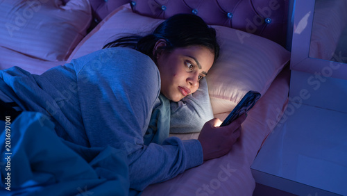 Indian Woman Using Phone Late at Night Lying in Bed in Dark Bedroom