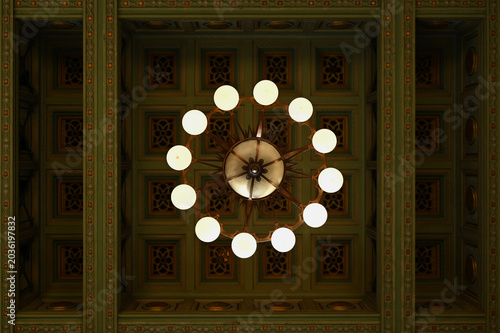 An elegant vintage chandelier hanging from an ornate patterned ceiling