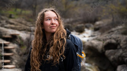 Portrait of a confident young female tourist with a backpack in the mountains.