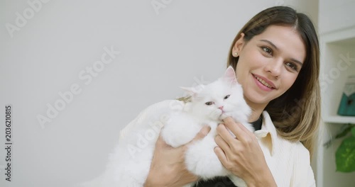 A young woman lovingly holds her fluffy white cat, smiling to express the joy and comforting connection found in pet ownership and serene domestic wellbeing.