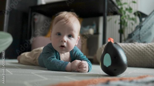 Adorable infant child looking at a roly-poly toy during playtime in nursery.