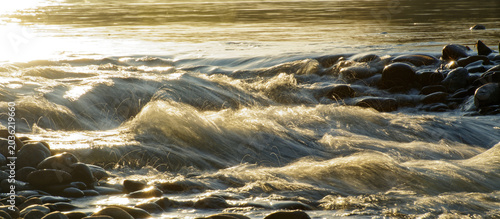 Konstfotografi warm golden hour backlit water spraying in slow motion from a waterfall