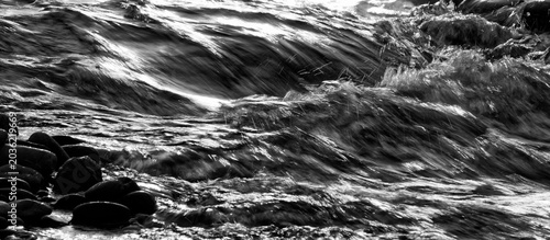 Black and white image of backlit water spraying in slow motion from a waterfall.