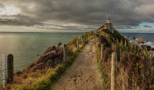 Konstfotografi Lighthouse on coastal path under dramatic storm clouds - White coastal lighthous