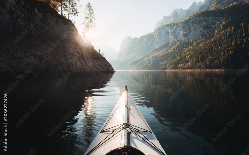 Obraz premium Kayaking on Gosausee lake with person standing one rocks against Dachstein mountain in the background at sunrise, Gosau, Salzkammergut region, Upper Austria, Austria 