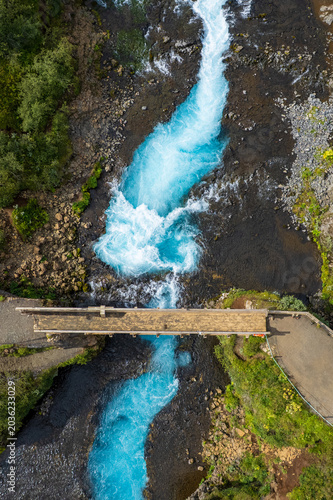 Stunning view of the Bruarfoss blue waterfall in Iceland, with turquoise water cascading over rocky terrain. Landscape of a tourist attraction and amazing travel destination.