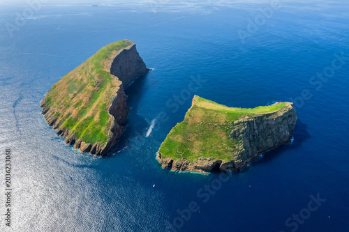Aerial view of Terceira islans in Azores, Portugal. Volcanic landscape.  Drone shot of rock formations on the Atlantic coast and  cabras islet. Green fields in rural environment.