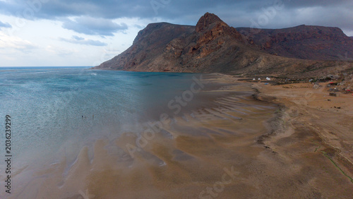 Remote beach and rocky mountains under cloudy sky