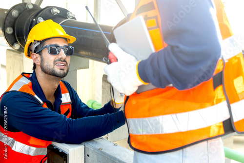 Billede på lærred Engineers with safety vests and helmets maintain a cooling tower on rooftop of solar farm