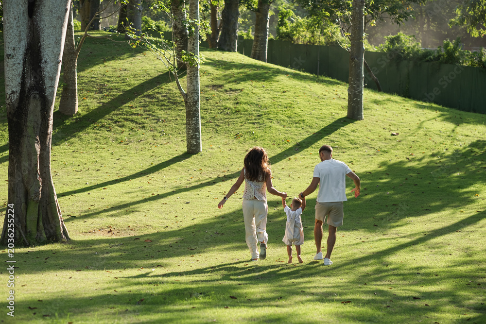 Fototapeta premium Family walking away together across tropical green landscape.