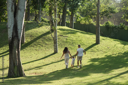 Family walking together in tropical park at sunset light.
