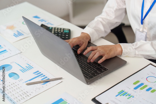 Foto Person typing on laptop with business data documents on office desk