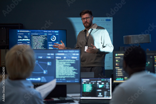 Foto Medium shot of Caucasian young adult man presenting cybersecurity data to team, explaining code and network monitoring workflow