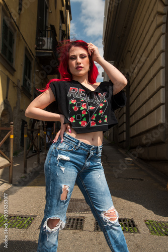 Young woman with red hair posing confidently in alley