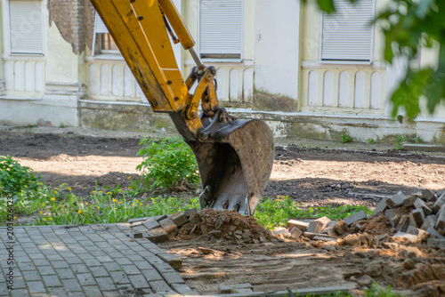 Cuadro en lienzo The photo captures the moment of construction or renovation work, where an excavator dismantles the paving stones on a busy street, creating the impression of progress and transformation