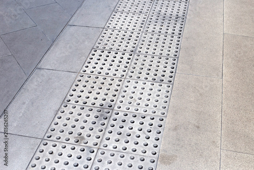 Bild auf Leinwand Tactile paving path with warning bumps for visually impaired people on a city sidewalk