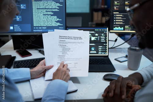 Cuadro en lienzo Close up of coworkers reviewing cybersecurity incident report and security logs beside coding dashboard, discussing risk analysis and compliance