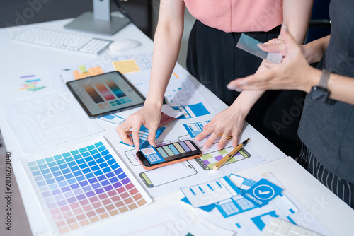 Fotografija UX developer and ui designer brainstorming about mobile app interface wireframe design with customer breif and color code at office