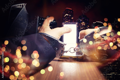 Tableau sur toile Double exposure of male hands locked in handcuffs with city landscape background, with cross processing filter