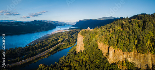 Aerial panoramic view of Columbia River Gorge with historic Vista House in golden evening light at sunset, Oregon, Pacific Northwest, USA