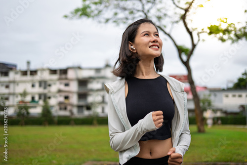 Asian Gen Z woman jogging in green urban park for wellness fitness and active city lifestyle