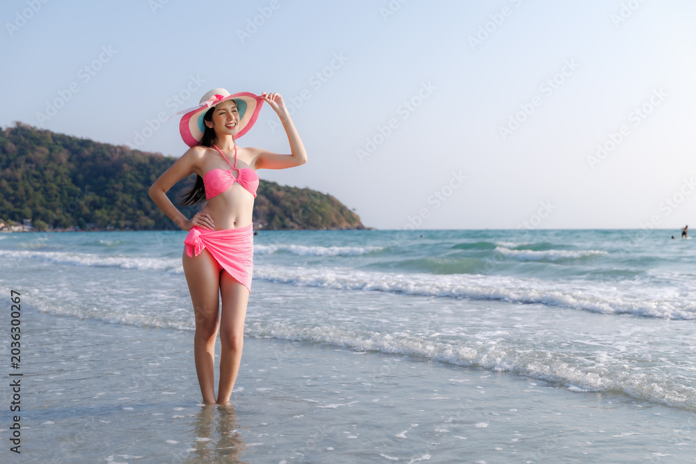Naklejka premium Young Woman In Pink Bikini And Sun Hat Posing In The Clear Tropical Waters Of Rayong Thailand