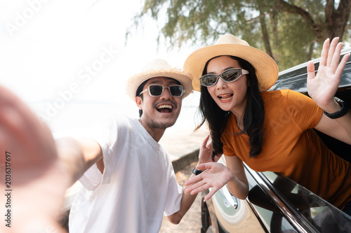 A happy couple enjoying a sunny road trip to the beach, smiling out the car window and embracing the freedom of travel together.