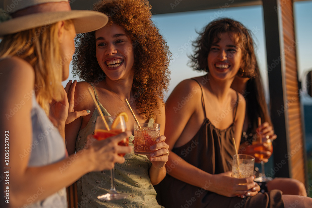 Obraz premium Women friends enjoying cocktails at summer sunset party