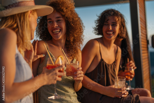 Women friends enjoying cocktails at summer sunset party