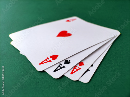 Full set of four aces isolated on a textured green surface.