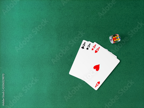 Four aces and one colorful die on a green surface.